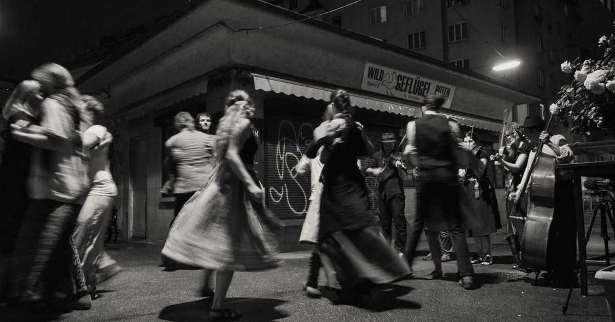 Tanzhausgeiger spielen nächtlich auf der Straße, Paare tanzen